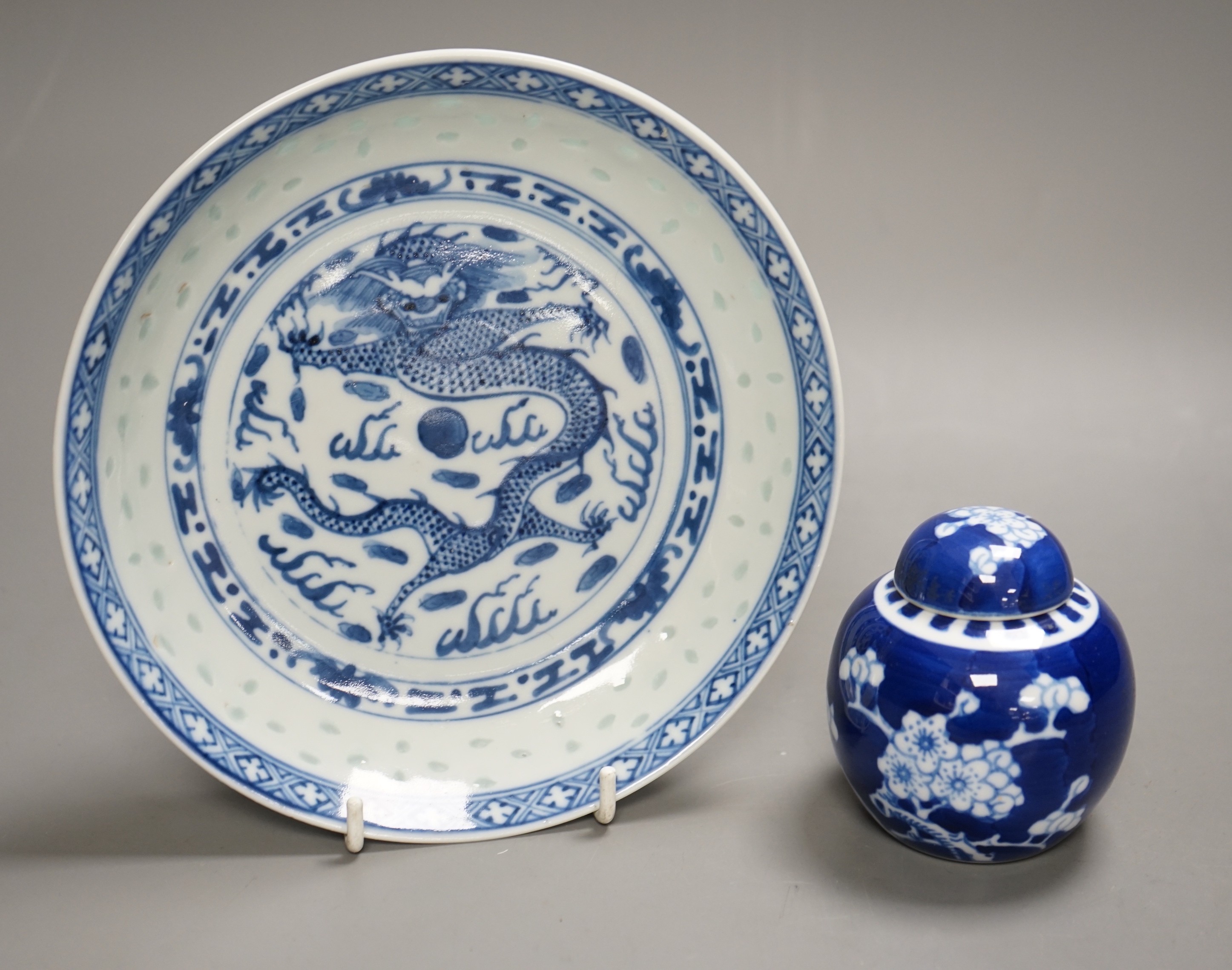 A Chinese blue and white dragon dish with rice grain border, early 20th century and a Chinese blue and white Prunus small jar and cover, dish 18cm diameter
